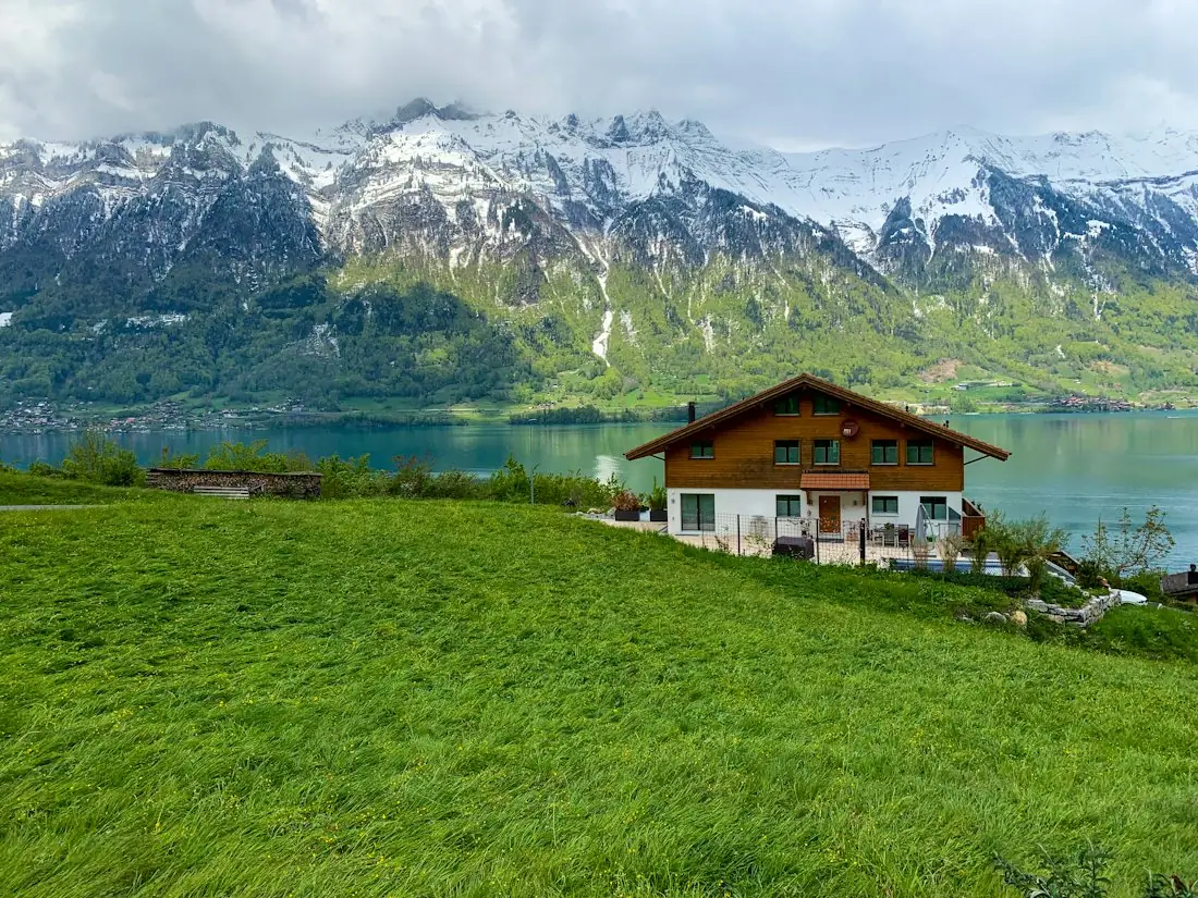 Chalet au bord d'un lac de montagne, sommets enneigés