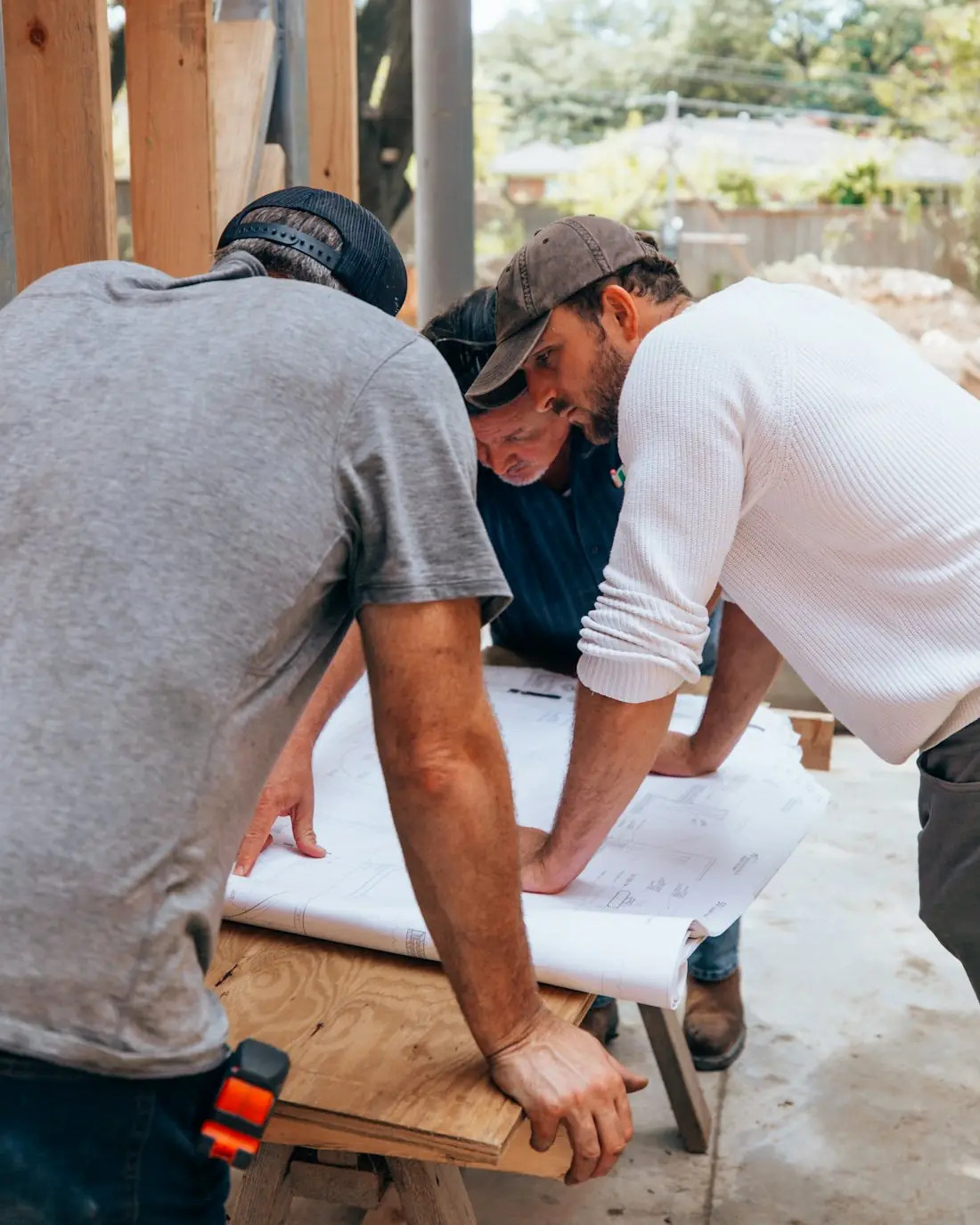 Artisans penchés sur les plans d'un chantier